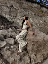 Pantalón largo de tiro alto, color beige con estampado vertical de líneas marrones. Corte ancho y fluido.