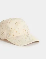 Gorra de béisbol color crema con bordado calado y estampado de flores en tonos pastel. Cuenta con visera curva y tira ajustable en la parte trasera.