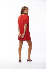 Vestido corto rojo con escote redondo, mangas cortas y solapas decorativas con botones metálicos en el frente.