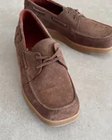 Zapato náutico de cuero vacuno color marrón con cordones y suela clara.
