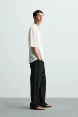 Camisa de manga corta con cuello bowling y calce relajado. Presenta un tejido con textura estructurada y efecto lavado, con cierre frontal de botones al tono.