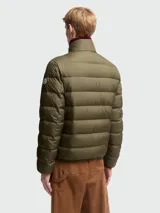 Chaqueta puffer Moncler modelo Baudinet en color verde militar. Presenta un diseño acolchado con costuras horizontales, cuello alto, cierre frontal de cremallera y bolsillos laterales. Incluye el parche con el logo de la marca en la manga izquierda.