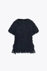 Top negro de punto con textura arrugada, cuello redondo, mangas cortas y lazos laterales.