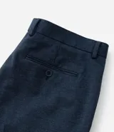 Pantalón de vestir gris claro con textura, de corte recto, con bolsillos laterales y traseros. Se ajusta a la cintura con cinturón de cuero negro.