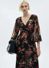 Vestido midi de gasa color negro con estampado floral en tonos rojos, rosados y verdes. Tiene escote en V, mangas largas abullonadas y corte evasé. Incluye cierre lateral y forro interior.