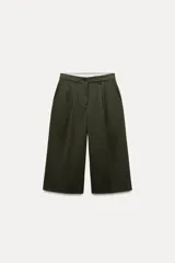Bermuda larga color verde oscuro de tiro medio y pierna ancha. Confeccionada en hilatura con 19% de lana. Presenta trabillas en la cintura, bolsillos laterales y con solapa en la espalda, pinzas en el delantero y cierre frontal con cremallera y botones.