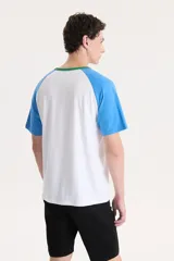 Remera blanca con mangas raglán celestes y cuello verde. Estampado frontal con la leyenda "San Francisco Since 1873" en celeste.