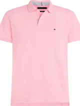Chomba rosada de Tommy Hilfiger, modelo 1985, de corte regular, con cuello tipo chomba, cartera de dos botones, mangas cortas y logo bordado en el pecho. El interior del cuello es rayado.