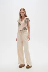 Pantalón de jean color beige, de tiro alto, corte palazzo y estilo paper bag.