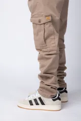 Pantalón cargo color beige con bolsillos laterales con solapa y botón. Corte ajustado.