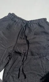 Pantalón negro de tiro alto, corte palazzo y cintura elastizada con cordón ajustable.