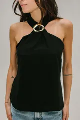 Blusa blanca de crepe twill con cuello halter y detalle de hebilla dorada en el escote.