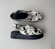 Suecos de cuero con estampado de vaca en blanco y negro, con plataforma de goma negra.