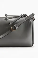 Cartera bandolera rectangular de cuero sintético color gris con cierre superior y correa ajustable.