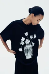Remera negra de algodón con cuello redondo y mangas cortas. Estampado frontal con un jarrón con flores en blanco y negro.