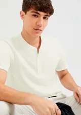 Camiseta color beige con cuello redondo abotonado y mangas cortas.