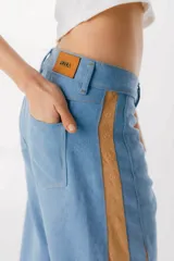 Pantalón de jean negro de pierna ancha con cortes en los laterales que van desde la pretina al bajo del pantalón. Por la mitad de la pierna presenta godets triangulares de encaje para darle mayor amplitud y detalles a la prenda.