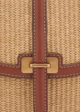 Bandolera de rafia color beige con detalles en cuero marrón, cierre de botón magnético y correa ajustable.