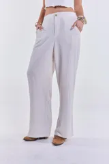 Pantalón de lino color beige, de corte recto y tiro alto, con cierre de botón y cremallera.