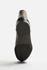 Bota Chelsea de cuero color marrón oscuro, con puntera fina, paneles laterales elásticos y tirador trasero.