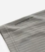 Remera deportiva de manga corta y cuello redondo, color beige claro, con textura acanalada vertical. Presenta detalles reflectantes en los hombros.