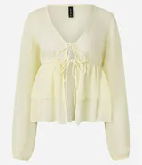 Blusa femenina de chiffon color amarillo pálido, con escote en V profundo, lazada ajustable en el centro del busto y mangas largas ajustadas. Presenta un diseño con volados en el ruedo.