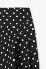 Falda midi negra con estampado de lunares blancos, de tiro alto y corte evasé.