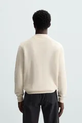 Polo marrón de corte relaxed fit, tejido en punto de algodón. Tiene cuello solapa con cierre frontal de botonadura, manga larga y acabados en rib.