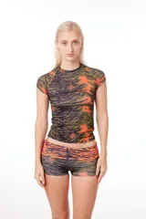 Remera anatómica de manga corta, confeccionada en tejido de poliéster con estampado de tigresa en tonos verde, naranja y negro.