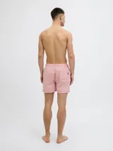 Short de baño rojo y blanco a rayas verticales, confeccionado en tejido seersucker. Cuenta con cintura elástica con cordón ajustable, bolsillos delanteros y un bolsillo trasero.