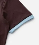 Remera de algodón color marrón con cuello redondo y ribetes en las mangas y cuello en color celeste. Presenta el número "86" estampado en grande en color celeste en el frente.