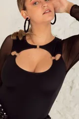 Body negro de lycra con mangas largas de microtul y detalle de aros metálicos en el escote.
