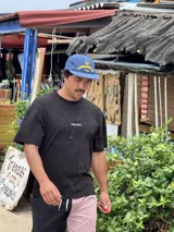 Gorra de béisbol azul marino con visera curva y bordado frontal en amarillo que dice "LOVE & PEACE" y debajo "PP:ONE".