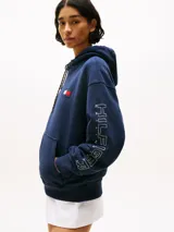 Buzo azul marino amplio con capucha y cordón distintivo, bolsillo canguro, puños y bajo de punto canalé, logo oversize de Tommy Hilfiger en la manga y la parte trasera, parche con logo de Tommy Hilfiger en el pecho y detalles distintivos de Hilfiger Sailing.