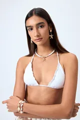 Top de bikini blanco con tirantes finos ajustables al cuello y a la espalda. Presenta volados en el escote y está confeccionado en tejido suave con acabado elástico.