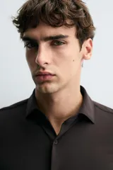 Camisa negra de manga larga con cuello italiano abierto y cierre frontal de botonadura. Corte slim fit.