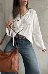 Blusa blanca de manga larga con detalles de encaje en el frente, mangas y cuello.