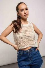 Blusa de tejido de punto calado color crema, sin mangas y corte crop.