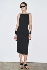 Vestido midi negro de tirantes finos, con cuello halter, detalle de drapeado y cierre con cremallera oculta.