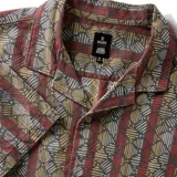 Camisa de manga corta con cuello cubano y estampado geométrico en tonos burdeos, gris y ocre.