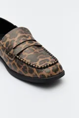 Mocasines negros de símil cuero texturizado, con punta cuadrada, detalle de bordado a tono en la capellada y taco de 2,5cm.