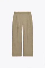 Pantalón de vestir color beige, de tiro alto con trabillas, bolsillos laterales y falsos bolsillos de vivo en la espalda. Presenta detalle de pliegues y cierre frontal con cremallera, botón interior y gancho metálico.