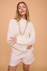 Buzo color crema tejido en algodón, de silueta holgada, mangas anchas y cuello bote.