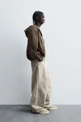 Pantalón de jean color beige, de corte amplio y tiro alto, con cinco bolsillos, efecto lavado y cierre frontal con botones.