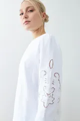 Sweatshirt rojo de manga larga con cuello redondo y calados bordados en los hombros y mangas.