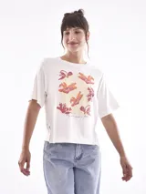 Remera blanca de corte recto con estampado de flores en tonos naranja y rosa.
