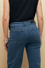 Pantalón de jean negro de corte recto con tachas plateadas en los laterales y tajos en el ruedo.