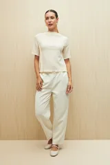 Top color crema de textura acanalada, con cuello semi alto y mangas cortas.