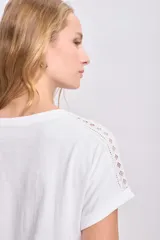 Remera blanca de manga corta con detalle de puntilla en el cuello y las mangas.