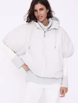 Campera corta color beige con capucha, cierre frontal con cremallera y mangas cortas. Diseño acolchado con patrón de rombos.